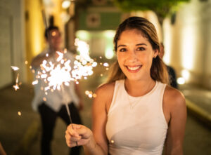 Portrait of young woman playing with sparklers on the street at night